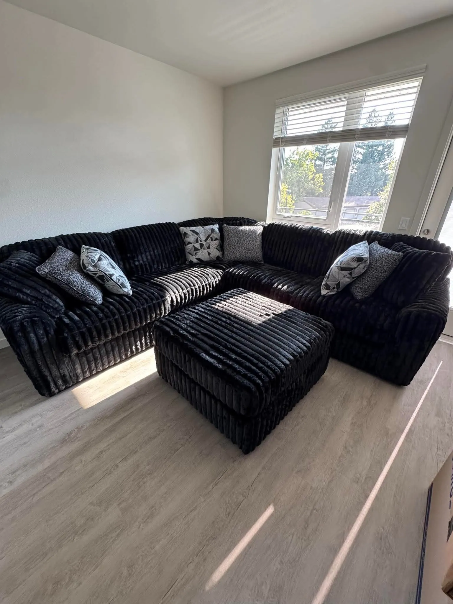 Black plush sectional with ottoman in a living room