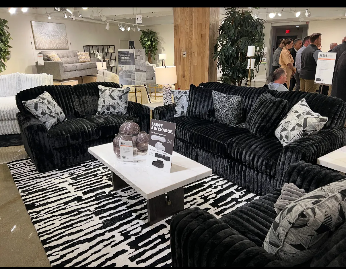 Black plush sectional styled in a living room with rug and wall art